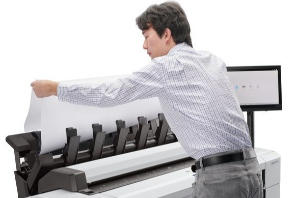 HP DesignJet T2600 with stacker and a man easily unloading architectural prints